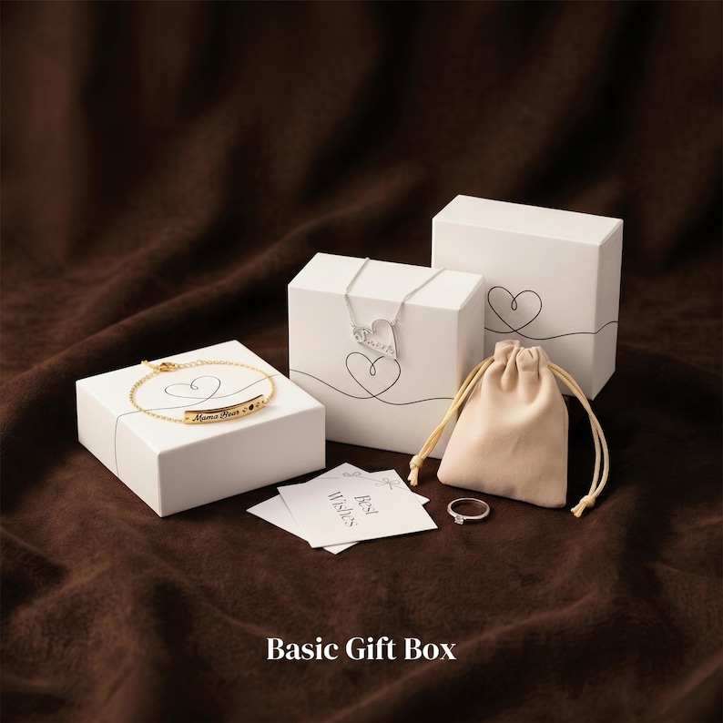 May include: A collection of jewelry and gift boxes on a brown surface. The items include a gold bracelet, a silver necklace, a ring, a drawstring pouch, and white boxes with heart designs. The text "Basic Gift Box" is at the bottom.