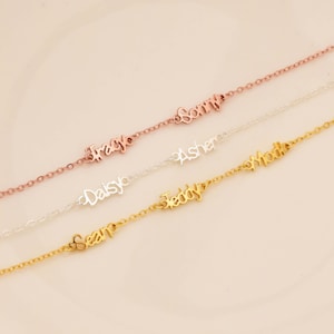 May include: A collection of delicate name bracelets in rose gold, silver, and gold. Each bracelet features a different name in a cursive font: Tracy, Sonny, Daisy, Asher, Sean, Teddy, and Mollie. The bracelets are displayed on a light pink background.
