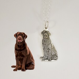 May include: A silver necklace with a pendant featuring a detailed, three-dimensional image of a brown Labrador Retriever sitting.