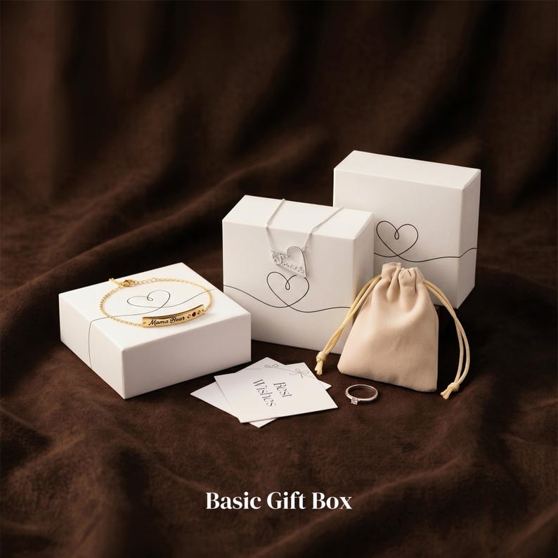 May include: A collection of jewelry gift boxes and accessories on a brown background. The image includes white boxes with heart designs, a gold bracelet, a silver necklace, a small beige pouch, a ring, and cards that say "Best Wishes". The text "Basic Gift Box" is at the bottom.