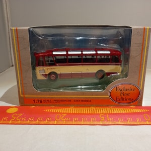May include: A red and cream 1:76 scale diecast model bus with the word "Nermum" printed on the side. The bus is in a clear plastic display case on a brown cardboard box with the words "Exclusive First Editions" printed on the side.
