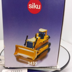 May include: A yellow Komatsu bulldozer model with black details, displayed in its original box. The box has the brand name "siku" in a red circle and the model number "3435". The bulldozer has a large front blade and track wheels.