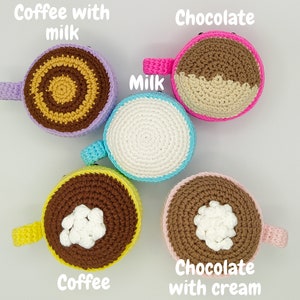 May include: Five crocheted coffee mugs in different colors and designs. The mugs are decorated with coffee, chocolate, milk, and cream. The mugs are labeled with the text "Coffee with milk", "Chocolate", "Milk", "Coffee", and "Chocolate with cream".