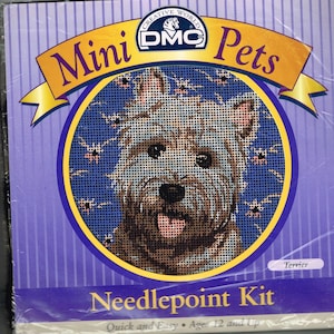 Puede incluir: Un kit de punto de cruz Mini Pets con un perro terrier. El empaque muestra las palabras "Mini Pets" y "Needlepoint Kit" encima y debajo de una imagen detallada del perro. El kit se describe como "Quick and Easy" y es adecuado para mayores de 12 años.