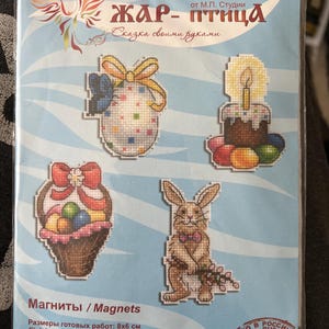 Könnte beinhalten: Eine Packung Kreuzstich-Magnete mit Ostermotiven. Die Designs umfassen ein Ei mit Schleife, einen Kuchen mit Kerze, einen Korb mit Eiern und ein Häschen mit Fliege. Fertige Größen sind 8x6 cm.