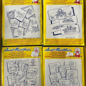 May include: Four yellow packages of iron-on transfers for crafts. Each package features a different design, including kittens, tea towels, pillow slips, and cross stitch kittens. The packages are labeled "Aunt Martha's Hot Iron Transfers" and include instructions for use.
