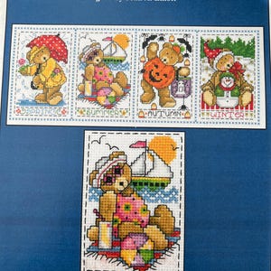 May include: A cross-stitch pattern sheet titled "SEASONAL TEDDIES" designed by Joan A. Elliott. The sheet features four seasonal teddy bear designs: Spring, Summer, Autumn, and Winter. The Summer design is shown in a close-up.