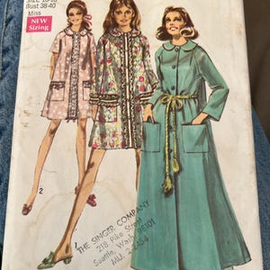 May include: A Simplicity sewing pattern envelope 8458 for size large 16-18, bust 38-40. The cover features illustrations of three different coat styles: a short pink patterned coat, a short floral coat, and a long solid teal coat with a rope belt.