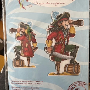 Könnte beinhalten: Ein Kreuzstich-Set mit zwei Piratenfiguren, die jeweils ein Fernrohr halten. Die Piraten tragen rote und schwarze Outfits. Die fertige Größe beträgt 19x12 cm (7.5" x 4.75"). Das Set enthält den Text "Жар-птица" und "Сказка своими руками".