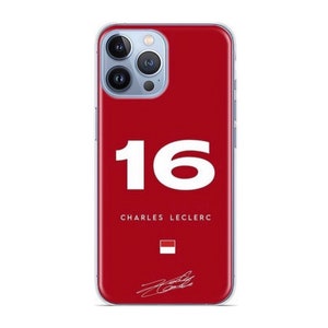May include: A red phone case with a white number "16" and the text "CHARLES LECLERC" in white. A small red and white flag and a signature are also visible.