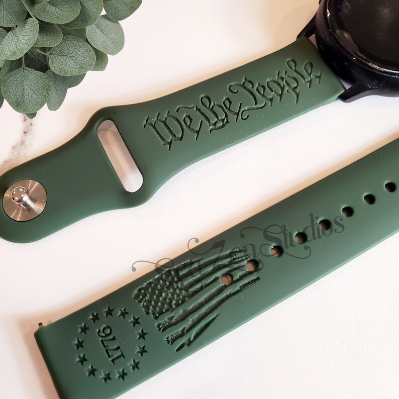 May include: Green silicone watch band with the text "We the People" and a design of the American flag with the text "1776" around it.