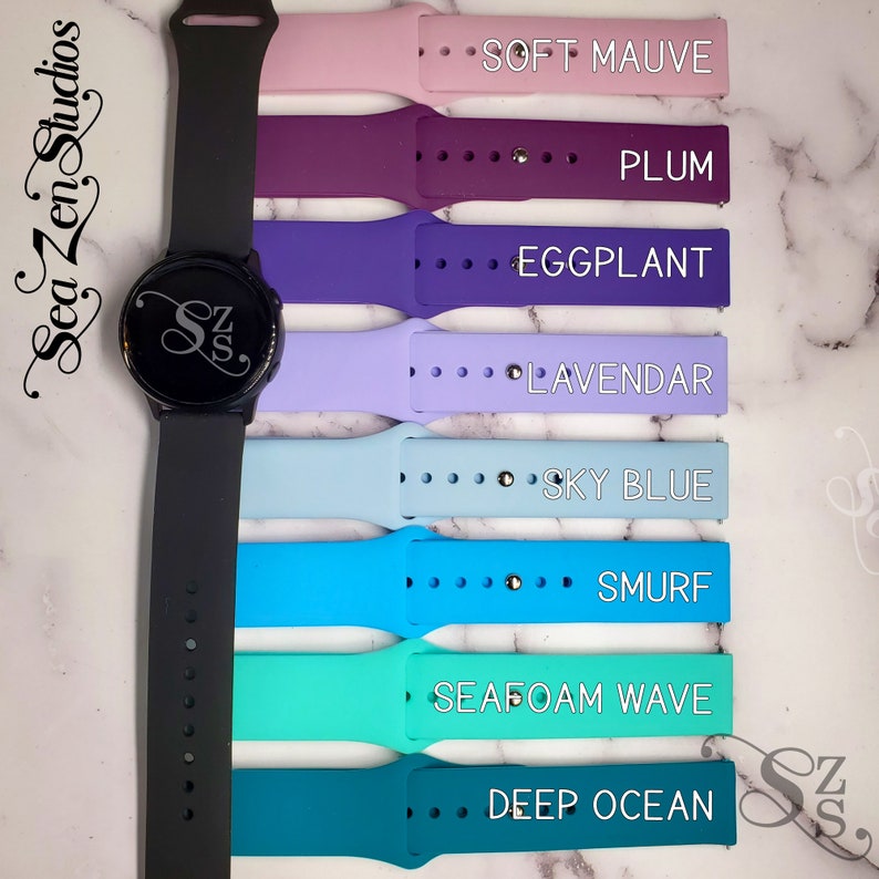 May include: A set of eight silicone watch bands in various colors, including soft mauve, plum, eggplant, lavender, sky blue, smurf, seafoam wave, and deep ocean. The bands are shown with a black smartwatch.
