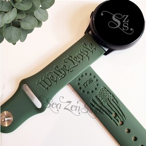 May include: Green silicone watch band with the text "We the People" and a design of the American flag with the year 1776.