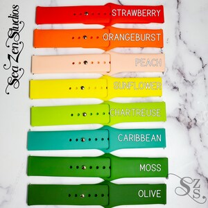 May include: Eight silicone watch bands in various colors, including red, orange, peach, yellow, green, teal, dark green, and olive green. Each band has the color name printed on it.