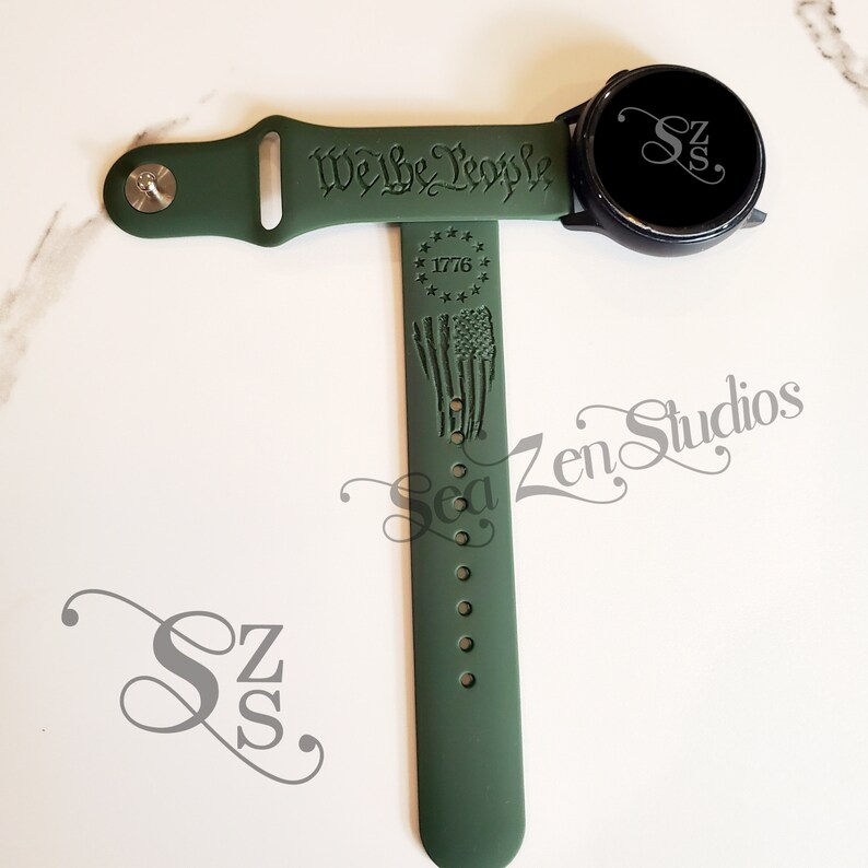May include: Green silicone watch band with the text "We the People" and a star-shaped design with the year 1776. The band also features a distressed American flag design.