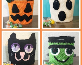 May include: Four crocheted Halloween trick-or-treat bags. The bags are shaped like a pumpkin, ghost, cat, and Frankenstein. Each bag has a different color and features a unique face.