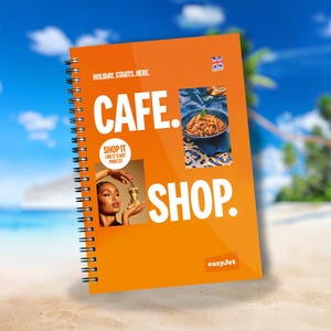 Op de afbeelding: Oranje boekje met de woorden "HOLIDAY. STARTS. HERE." en "CAFE. SHOP." in grote witte letters. Het boekje heeft een spiraalbinding en een klein easyJet-logo rechtsonder. Er zijn twee kleinere afbeeldingen op de omslag: een vrouw die een gouden fles vasthoudt en een kom pasta.