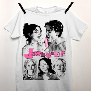May include: White t-shirt with a black and white graphic print of a couple and three women. The graphic includes the text "Jawbreaker" in pink.