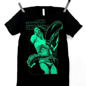 May include: Black t-shirt with a green graphic print of a woman and an alien creature from the movie "Alien". The text "Nostromo 1805 1979" is printed on the shirt.