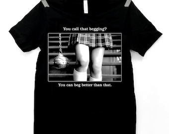 May include: Black t-shirt with a graphic featuring a black and white image of a person's legs in a plaid skirt and the text "You call that begging? You can beg better than that."