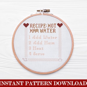 May include: A cross-stitch pattern in a wooden embroidery hoop. The design features the text "RECIPE: HOT HAM WATER" with instructions: "1 Add Water, 2 Add Ham, 3 Heat, 4 Serve." Two heart symbols are at the top. The words "INSTANT PATTERN DOWNLOAD" are at the bottom.