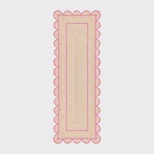 Peut inclure: Un tapis de couloir rectangulaire en jute avec une bordure festonnée rose et une bordure intérieure rose assortie. Le tapis est de couleur beige naturel et a une texture tissée.