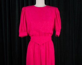 May include: A hot pink dress with a fitted bodice and a slightly flared skirt. The dress has a small, pointed collar and short, puffed sleeves.
