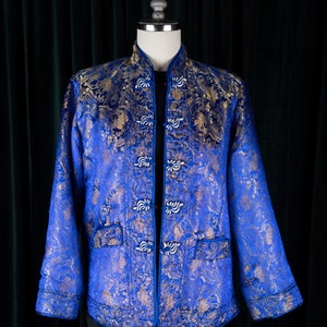May include: A blue and gold brocade jacket with a mandarin collar and decorative buttons. The jacket is quilted and has a traditional Chinese design.