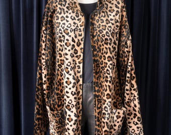 May include: A brown and tan leopard print jacket with a zipper closure. The jacket has two pockets on the front and is made of a soft, plush fabric.
