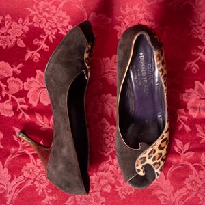 K&ouml;nnte beinhalten: Ein Paar Donald J Pliner Couture Peeptoe-Pumps aus dunkelbraunem Wildleder mit Leopardenmuster-Akzenten. Das Innere des Schuhs ist dunkelviolett und zeigt den Markennamen sowie einen Hinweis auf die Herstellung in den Bergen Italiens.