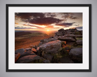 May include: A panoramic view of a rocky landscape at sunset. The sun is setting behind the horizon, casting a warm glow over the scene. The rocks are large and jagged, and they are scattered across the landscape. The sky is a mix of orange, pink, and purple.