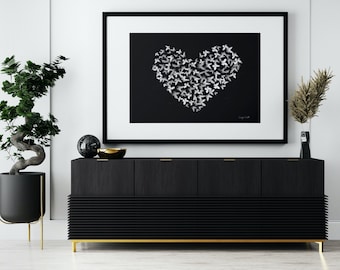 Könnte beinhalten: Ein schwarz-weiß gerahmter Druck eines Herzens aus Schmetterlingen auf schwarzem Hintergrund. Der Druck hängt über einem schwarzen Sideboard mit goldenen Akzenten.