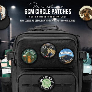 May include: A black tactical backpack featuring multiple circular 6cm patches with custom full-colour printed designs and text, including mountain landscapes and hiking themes. The patches have hook backing and are attached to the front panel.