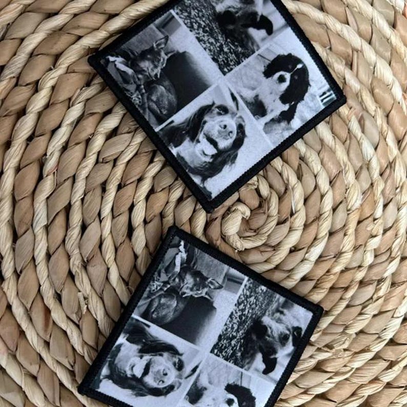 May include: Two square coasters with black borders, each featuring a collage of four black and white dog photos. The coasters are placed on a woven, circular placemat with a natural color.