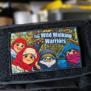 May include: A rectangular patch with the text "The Wild Walking Warriors" above a colorful cartoon illustration of four characters. The patch is bordered by black fabric with a hook and loop fastener.