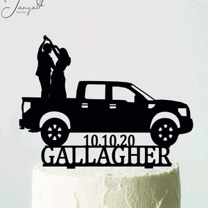 Può includere: Decorazione nera per torta con la silhouette di un pick-up e una coppia che balla. La data "10.10.20" e il nome "Gallagher" sono visualizzati sotto. La torta è su un supporto bianco.