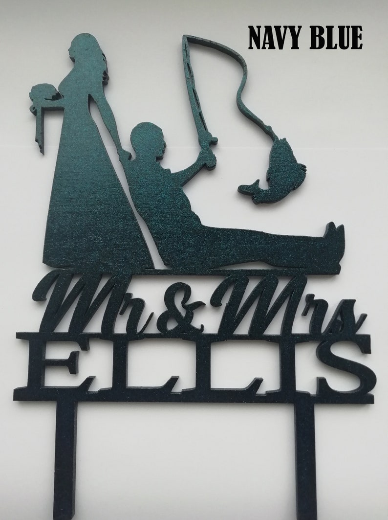 May include: Navy blue wedding cake topper featuring a bride and groom silhouette, with the groom fishing. The topper includes the text "Mr & Mrs ELLIS". The bride is holding a bouquet. The fishing rod has a fish on the end.