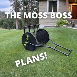 May include: A black metal moss roller with a green "Moss Boss" logo on the side. The roller is on a green lawn with the text "PLANS!" in white letters. The text "THE MOSS BOSS" is in white letters on a house in the background.
