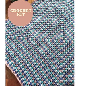 Może przedstawiać: Zestaw do szydełkowania koca z wzorem romb&oacute;w w kolorze niebieskim, r&oacute;żowym i białym. Tekst "CROCHET KIT" znajduje się na r&oacute;żowym kole.