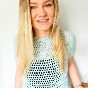 May include: A light blue crochet top with a loose, open-weave pattern. The top has short sleeves and a round neckline.