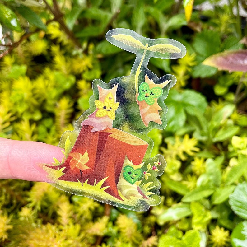 May include: Three adorable cartoon characters with leaf-like features are sitting on a tree stump. The character on the left has a yellow star on its head, the character in the middle is holding a green leaf umbrella, and the character on the right has a green heart on its head.