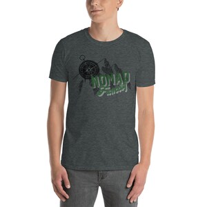 May include: A dark heather grey t-shirt with a compass, mountains, and the text "NOMAD  Famously" in green and black.