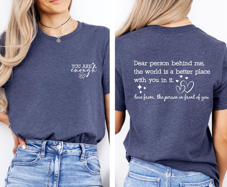 May include: A navy blue t-shirt with a white graphic on the front that says "YOU ARE enough" with a heart symbol. The back of the shirt has a white graphic that says "Dear person behind me, the world is a better place with you in it. love from, the person in front of you" with a heart symbol.