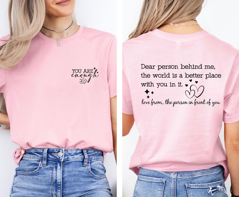 May include: Pink t-shirt with the text "YOU ARE enough" on the front and "Dear person behind me, the world is a better place with you in it. love from, the person in front of you" on the back.