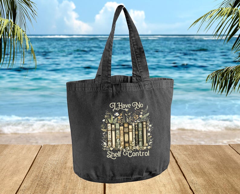A black tote bag with a printed design on it, featuring a beach scene with palm trees and the ocean in the background.