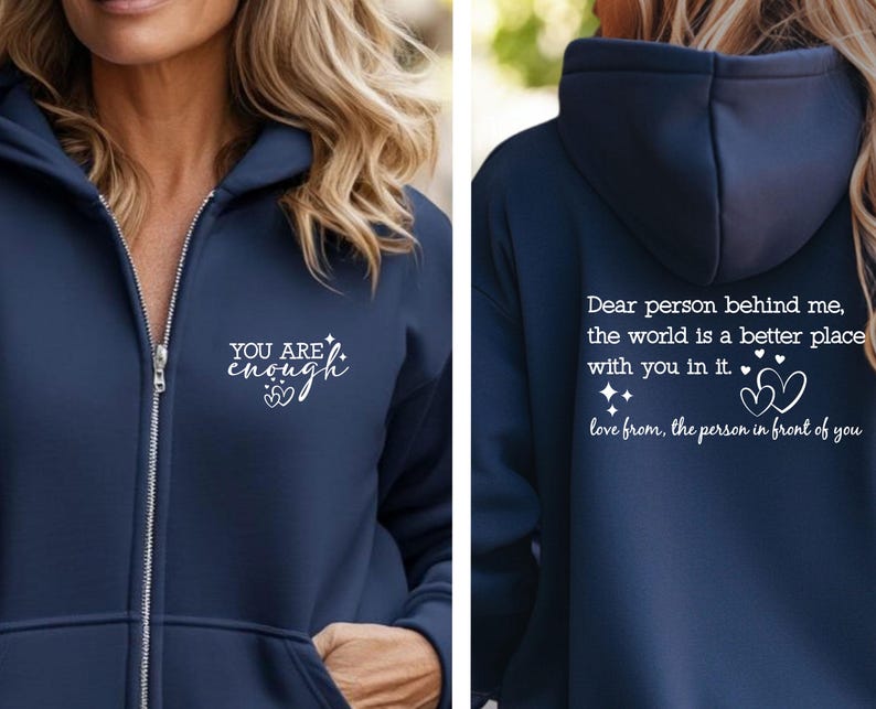 May include: Navy blue zip-up hoodie with white text that reads "YOU ARE enough" on the front. The back of the hoodie has the text "Dear person behind me, the world is a better place with you in it. love from, the person in front of you."