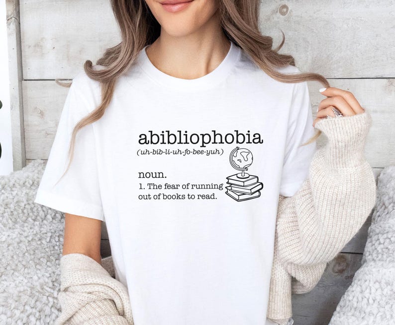 May include: White t-shirt with the text "abibliophobia (uh-bib-li-uh-fo-bee-yuh) noun. 1. The fear of running out of books to read." and a drawing of a globe on top of a stack of books.