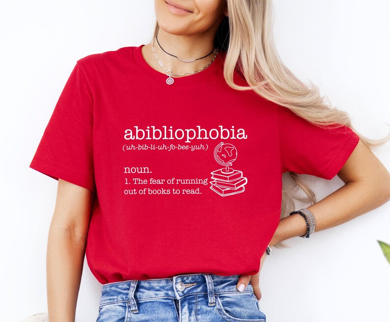 May include: Red t-shirt with white text that reads "abibliophobia (uh-bib-li-uh-fo-bee-yuh) noun. 1. The fear of running out of books to read."