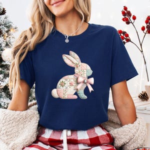 May include: Navy blue t-shirt featuring a patchwork bunny design with a pink bow. The bunny is composed of pastel floral and geometric patterns. The shirt is a comfortable, casual style.