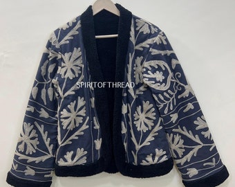 May include: A navy blue jacket with a black collar and cuffs. The jacket is embroidered with white floral designs and has a sherpa lining. The text "SPIRITOFTHREAD" is visible on the jacket.